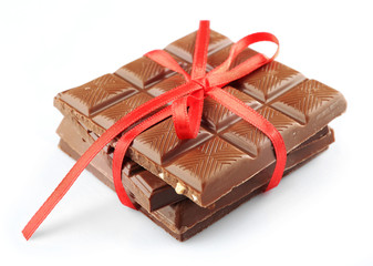 Milk chocolate bar with red bow on color wooden background