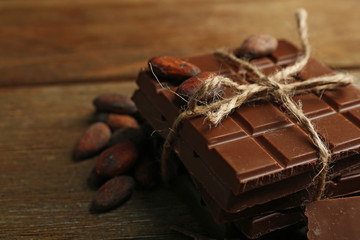 Chocolate pieces, shavings and cocoa beans on color wooden background