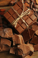 Chocolate pieces, shavings and cocoa beans on color wooden background