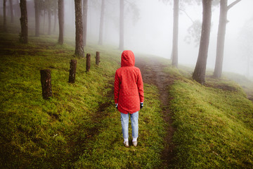 woman wear red coat  turn back on path way with fog