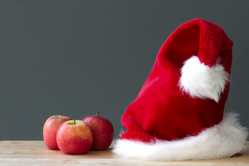 Obraz na płótnie Canvas Santa Claus Christmas red hat and three apples fruit on table