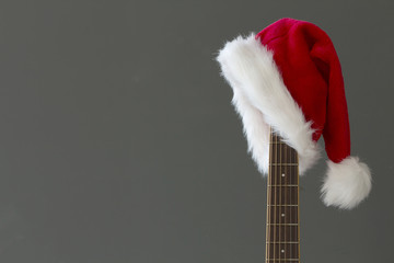 Red Christmas hat on guitar with grey background, Merry Christmas song