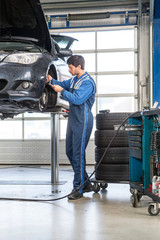 Mechanic, working on a car, checking the thickness of the brake