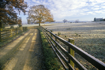 Fototapeta premium Morning view of a country road and wood fence in Upper Brails, England