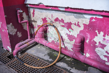 pink pipes with cracked old wall