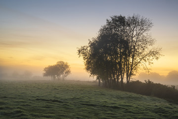 Stunning vibrant Autumn foggy sunrise English countryside landsc