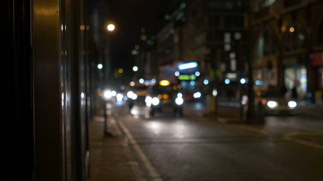 Buses, cars, bikes, taxi with headlights on running in the night through the streets of London.