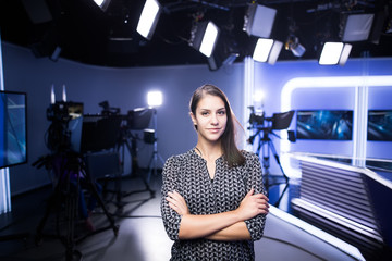 Young beautiful brunette television announcer at studio standing next to the camera.TV director at...