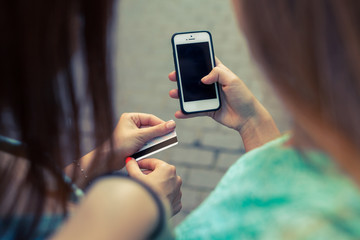 Close up of smartphone and credit card holding by girls.