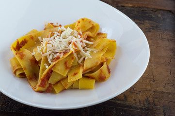 Pappardelle al pomodoro fresco fatte in casa su piatto e tavolo in legno antico, pasta italiana fatta in casa