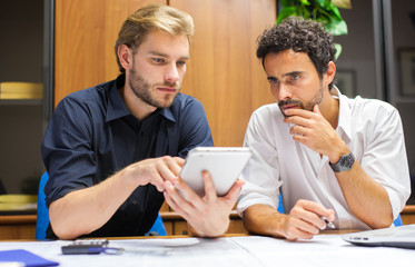 Two colleagues looking at a tablet in the office