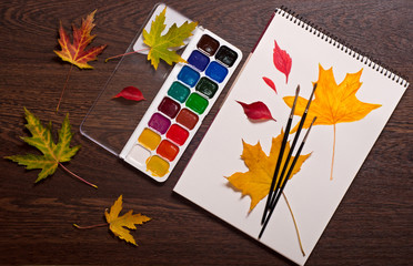 album, watercolor paints, brushes and autumn leaves