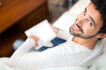 Man using a tablet while relaxing on the couch