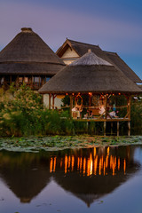 Landscape of wooden bower on the lake with water lilies in the sunset.