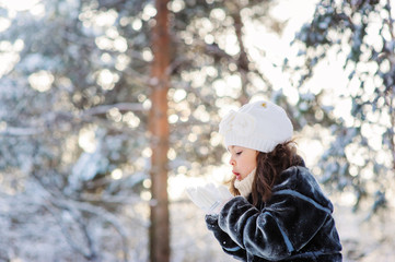 child girl playing with snow on cozy winter forest walk