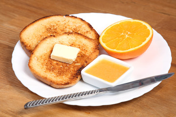 european served breakfast: toasts with jam, butter and orange