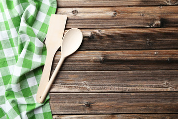 Empty wooden table with wooden spoon and napkin on brown backgro
