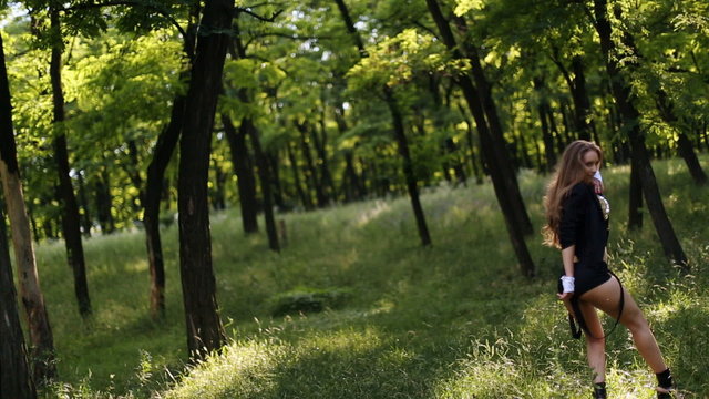 girl in black shorts dancing in the forest back to the camera