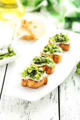 Tasty fresh bruschetta on plate on white wooden background