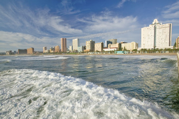 Naklejka premium Ocean wave comes in Durban skyline, South Africa on the Indian Ocean