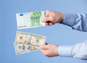 Businessman comparing hundred dollars and hundred euro