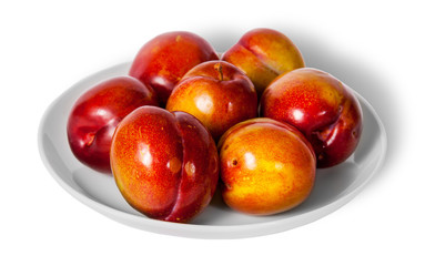 Red and yellow plums on white plate