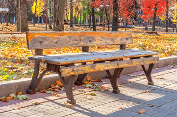 Lonely old bench in autumn city park on a sunny day