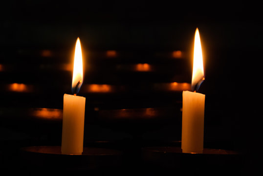 Two burning candles on a dark background