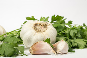 Bulb and cloves of garlic beside fresh parsley, on white