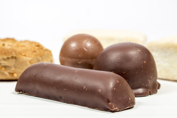 Shortbread bar covered by black chocolate beside a coconut bonbon, a chocolate ball and other spanish Christmas sweets