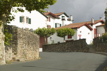 Road to Sare, France in Basque Country on Spanish-French border, is a hilltop 17th century village surrounded by farm fields, in the Labourd province. It is centered around the Place du Fronto. The houses are built in the traditional style of the region, with shutters painted colors red and green of the Basque flag. Close to St. Jean de Luz, on the Cote Basque, France.