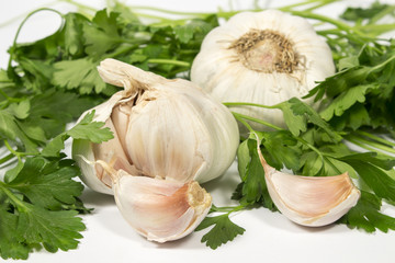 Garlic cloves, bulbs and parsley leaves, on white background