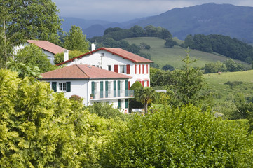 Fototapeta na wymiar Sare, France in Basque Country on Spanish-French border, is a hilltop 17th century village surrounded by farm fields and mount Rhune in the Labourd province. The houses are built in the traditional style of the region, with shutters painted colors red and green of the Basque flag. Close to St. Jean de Luz, on the Cote Basque, France.