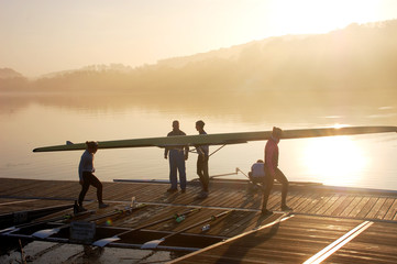 Ruderer tragen am frühen Morgen ein Boot zu Wasser