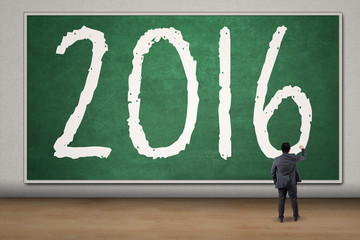 Businessman write numbers 2016 on the blackboard
