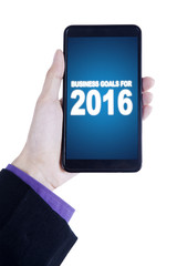 Hand holds cellphone with business goals for 2016