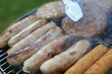 sausages and burgers cooking on barbecue