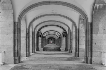 Symmetrical corridor with rows of columns. Black and white photo.