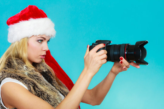 Photographer girl in santa claus hat shooting images