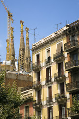 Fototapeta na wymiar Apartments in foreground with view of Sagrada Familia Holy Family Church by architect Antoni Gaudi, Barcelona, Spain begun in 1882 and continuing to be built into the 21st Century