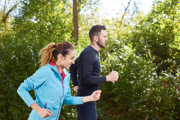 Young running couple jogging in autumn nature