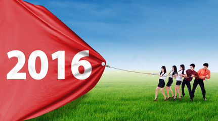 Young businesspeople takeover flag with numbers 2016