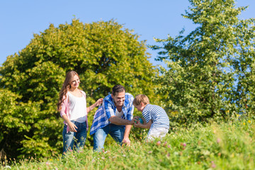 Familie spielt Ball auf Wiese im Sommer