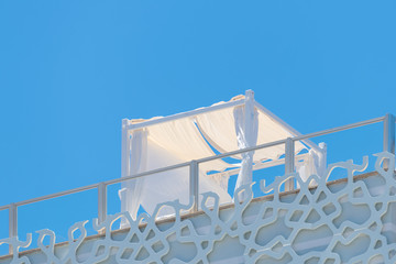 Lounge area with white pavilion on roof top. Sunbed for honeymoon on a sunny day against blue clear sky © HBpictures