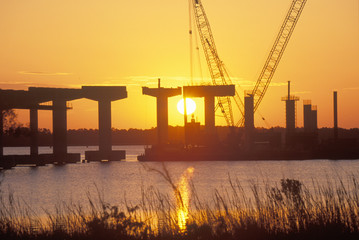 Obraz premium A sun rising behind a bridge building site in New Bern, North Carolina