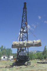 A crane raising a weathered log as part of a reenactment of the workings of a 19th century lumber mill