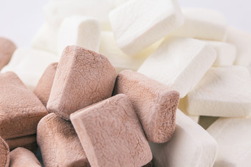 Pile of chocolate and original flavours of marshmellows in red pastel background - close-up