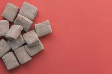 Pile of chocolate marshmallows in red pastel background.