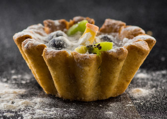 Delicious tartlet with fruit on black background