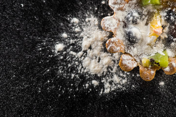 Delicious tartlet with fruit on black background